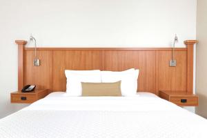 a bedroom with a white bed with a wooden headboard at Wyndham Garden Hotel Austin in Austin