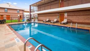 a swimming pool with two chairs and a building at Best Western Executive Inn in Marshall
