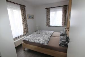 Un dormitorio con una cama y dos ventanas. en Ferienwohnung Maigloeckchen 17, en Ostseebad Karlshagen
