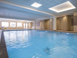 a large swimming pool with blue water in a building at Résidence L'Altaviva in Les Boisses