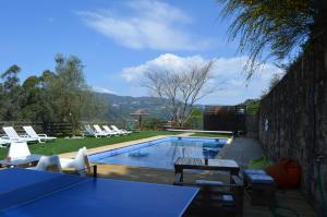 a swimming pool with chairs and a table at Villa de Paco in Sever do Vouga