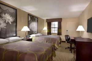 a hotel room with two beds and a desk at Super 8 by Wyndham Ruston in Ruston