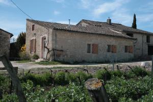 an old stone house with a fence in front of it at AU NID DES VIGNES in Cahuzac-sur-Vère