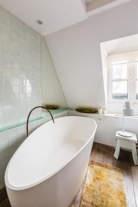 a white bath tub in a bathroom with a window at Veeve - Retro Cool on Rue Saint Paul in Paris