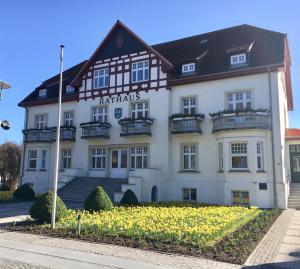 a large white building with a black roof at Fewo Strandstraße - führt auf die schöne Ostsee-Seebrücke in Kühlungsborn