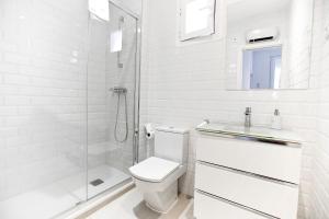 y baño blanco con aseo y ducha. en Apartamento Malasaña I, en Madrid