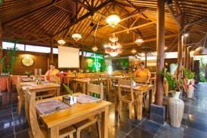 een restaurant met houten tafels en stoelen en mensen bij Ubud Raya Shala in Ubud
