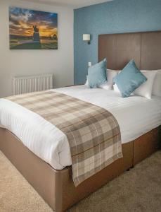 a bedroom with a large bed with blue pillows at King Robert Hotel in Stirling