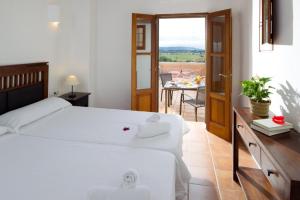 een slaapkamer met een groot wit bed en een tafel bij CAN NOVES - Villa de 2 suites (3) in Sant Francesc Xavier