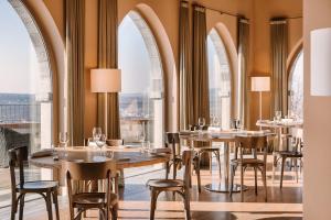 um restaurante com mesas e cadeiras e janelas grandes em Tenuta De L'Annunziata - Natural Relais em Uggiate