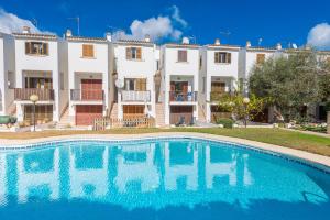 una villa con piscina frente a un edificio en Es Mallorqui, en Puerto de Alcudia