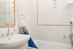 a white bathroom with a sink and a tub and a sink at Coliseum top floor with terrace and view in Rome