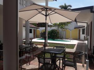 eine Terrasse mit Tischen, Stühlen und einem Sonnenschirm in der Unterkunft Hotel Casa Jardin in Asunción