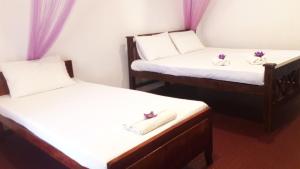 two twin beds in a room with purple curtains at Richwin Villa Dambulla in Dambulla