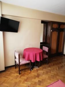 Habitación con mesa, sillas y TV. en Hotel La Joya, en La Paz