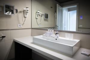 y baño con lavabo blanco y espejo. en Parc Hotel Germano Suites & Apartments, en Bardolino