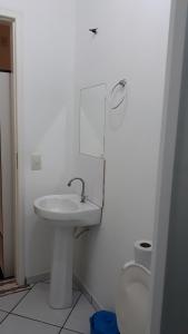 uma casa de banho branca com um lavatório e um WC em Urussanga Hotel em Urussanga