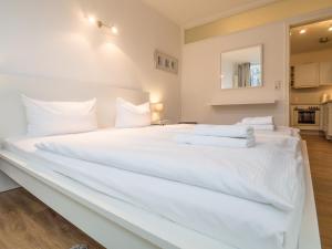 a large white bed with white sheets and pillows at Appartement Nr 7 im Sonnenbad in Sassnitz