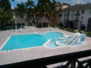 a large swimming pool with a slide and stairs in front of a building at Cool's 1 bedroom Beach & Garden View in Ocho Rios