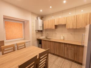 a kitchen with wooden cabinets and a wooden table at Apartamenty ZYGFRYD 28C 2 in Bystrzyca Kłodzka