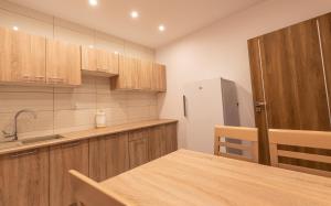 a kitchen with wooden cabinets and a table and a refrigerator at Apartamenty ZYGFRYD 28C 2 in Bystrzyca Kłodzka