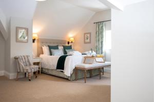 a bedroom with a large bed and a chair at The Farmhouse at Bodnant Welsh Food in Conwy