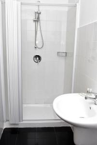 Un baño blanco con ducha y lavabo. en Rooms Plaza, en Marina di Camerota