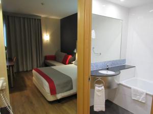 um quarto de hotel com uma cama e uma banheira em Holiday Inn Express Málaga Airport, an IHG Hotel em Málaga