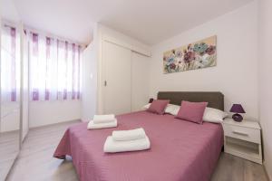 ein Schlafzimmer mit einem rosa Bett mit zwei weißen Hockern darauf in der Unterkunft Apartman Ankica in Kaštela