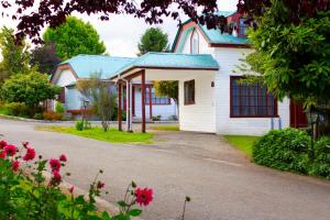 a white house with a blue roof and a driveway at Hotel y Cabañas Molino Viejo in Puerto Varas