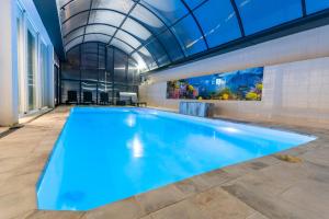 a large swimming pool in a building with a glass ceiling at Luxurious Villa Marly III to two minutes the beach in Castelldefels