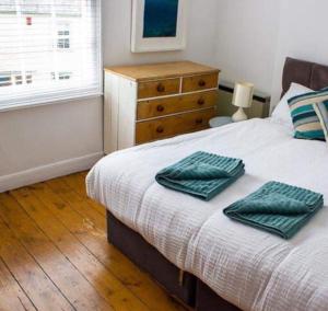 a bedroom with a bed with two green towels on it at Drang house all rooms have stairs in Padstow