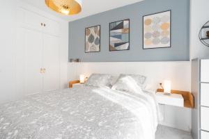 Un dormitorio blanco con una cama y algunas fotos en la pared en Homemálaga Penthouse Victoria, en Málaga