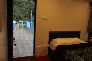 - une chambre avec un lit et une porte donnant sur une terrasse dans l'établissement FRATERNITY HOMESTAY, à Darjeeling