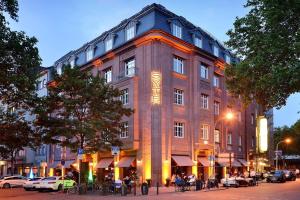 a large building with people sitting outside of it at Syte Boutique Hotel Mannheim in Mannheim