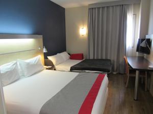a hotel room with two beds and a desk at Holiday Inn Express Málaga Airport, an IHG Hotel in Málaga