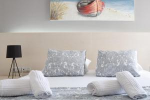 ein Schlafzimmer mit einem Bett mit Kissen und einem Gemälde in der Unterkunft Poseidon by Heloni Apartments in Piräus