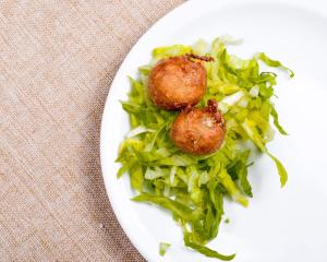 a plate of food with meatballs and greens on a table at Hotel Biobistro Semadeni in Poschiavo