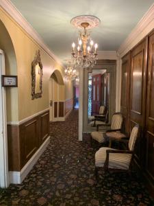 einen Flur mit einem Kronleuchter und Stühlen in einem Gebäude in der Unterkunft Hotel Villa Convento in New Orleans
