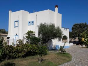 um edifício branco com uma árvore em frente em Elafonisos: Two storey house on the sea front em Elafonisos