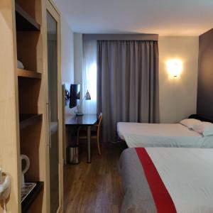 ein Hotelzimmer mit 2 Betten und einem Schreibtisch in der Unterkunft Holiday Inn Express Málaga Airport, an IHG Hotel in Málaga