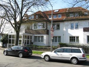 zwei Autos, die vor einem weißen Haus geparkt sind in der Unterkunft Hotel Eilenriede in Hannover