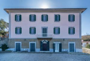 a large white building with green shutters at Villa Eugenia in Livorno