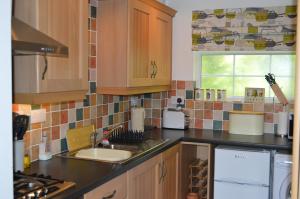 a kitchen with wooden cabinets and a sink and a window at Bumble Bee Cottage in Hartland
