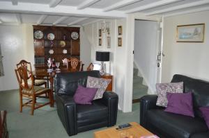 uma sala de estar com duas cadeiras de couro e uma mesa em Bumble Bee Cottage em Hartland