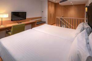 - duże białe łóżko w pokoju z biurkiem w obiekcie Apartments Playa de Castelldefels w mieście Castelldefels