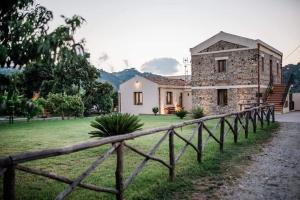 a stone house with a fence in front of it at Valle degli Agrumi in San Pier Niceto