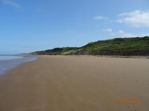 an empty beach with a hill in the background at La ferme aux chats in Formigny