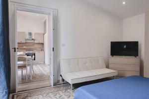 a living room with a white couch and a television at Appartamenti Luxury Greco in Brindisi