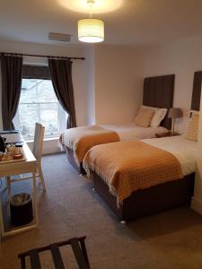 a bedroom with two beds and a table and a desk at Ty Helyg Guest House in Brecon